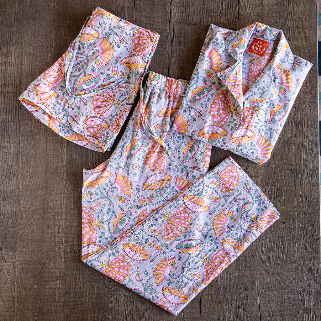 Four piece black cotton pajama set featuring button down top, shorts, pants and matching tote.