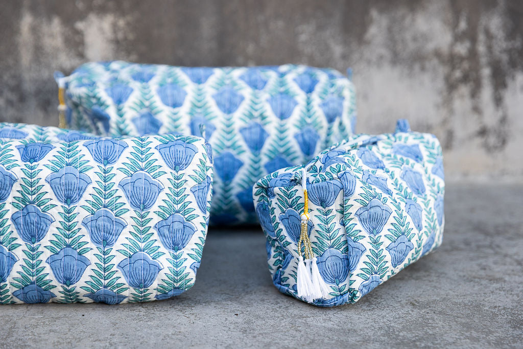 Set of three multi-colored patterned cotton cosmetic bags. Smaller bags fit into the largest for easy storage. Blue floral on white.