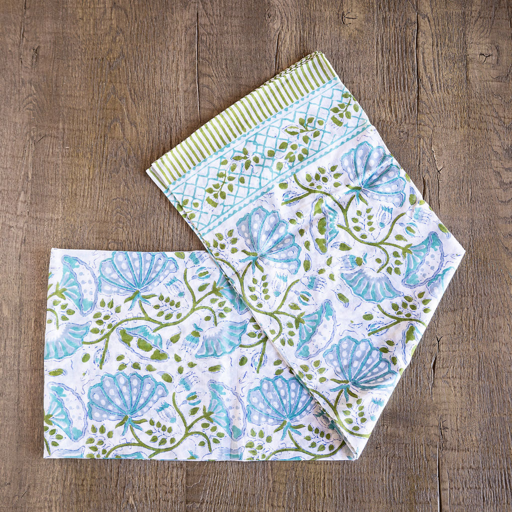 Image of model displaying Tuk and Lu's Sarong. Can be use as a shawl or cover up. Blue and green floral design on white.