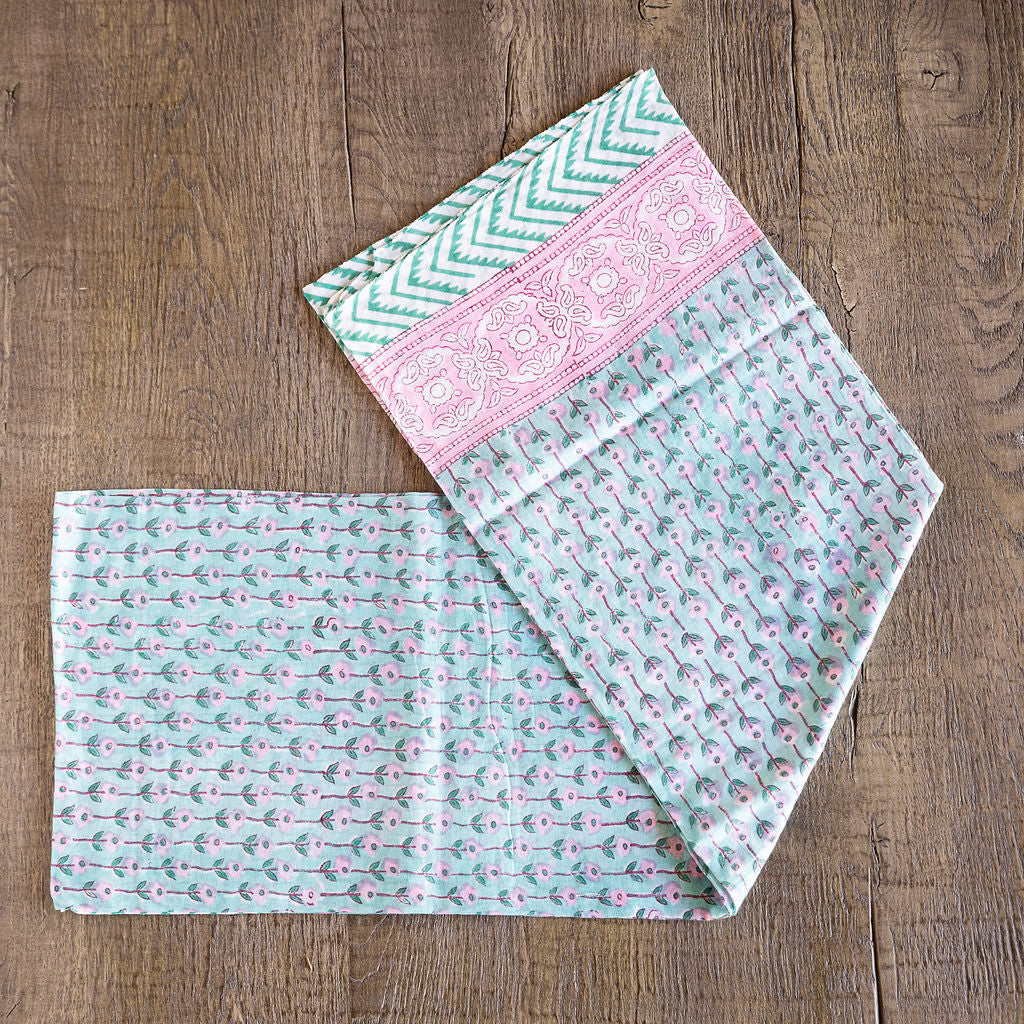 Image of model displaying Tuk and Lu's Sarong. Can be use as a shawl or cover up. Delicate pink flowers on a light green background.
