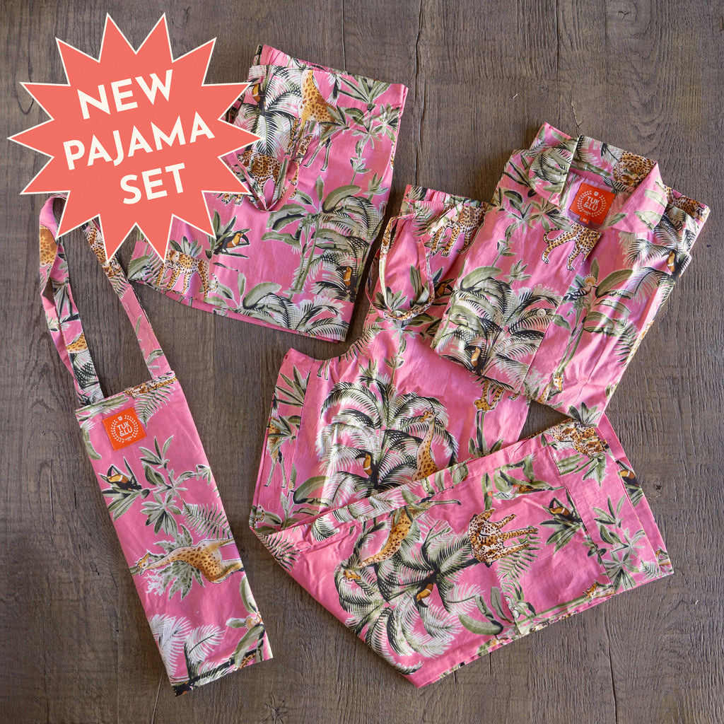 Four piece cotton pajama set featuring button down top, shorts, pants and matching tote.  PJ's have a pattern of pink background with palm trees, gazelles leopards and toucans
