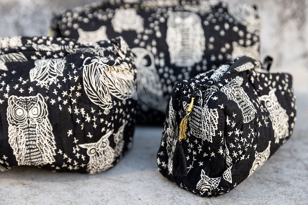 Set of three multi-colored patterned cotton cosmetic bags. Smaller bags fit into the largest for easy storage. Owl pattern on black. Detail