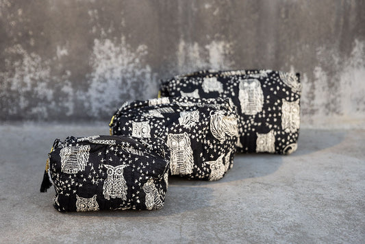 Set of three multi-colored patterned cotton cosmetic bags. Smaller bags fit into the largest for easy storage. Owl pattern on black.
