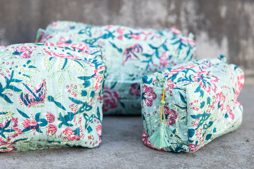 Set of three multi-colored patterned cotton cosmetic bags. Smaller bags fit into the largest for easy storage. Floral pattern on celadon green. Detail