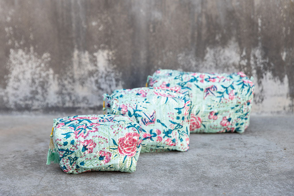 Set of three multi-colored patterned cotton cosmetic bags. Smaller bags fit into the largest for easy storage. Floral pattern on celadon green.