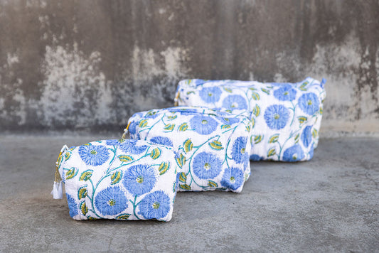Set of three multi-colored patterned cotton cosmetic bags. Smaller bags fit into the largest for easy storage. Blue floral on white.