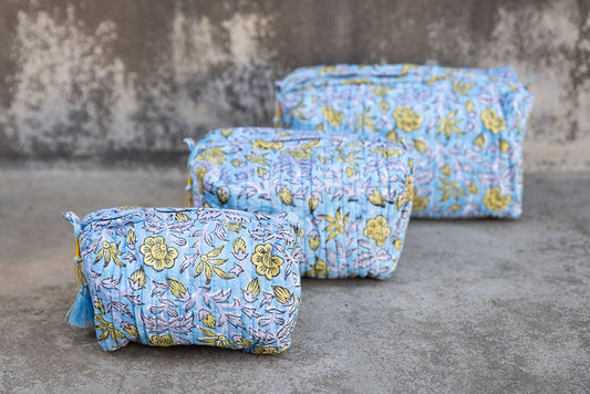 Set of three multi-colored patterned cotton cosmetic bags. Smaller bags fit into the largest for easy storage. Yellow Floral design on blue.