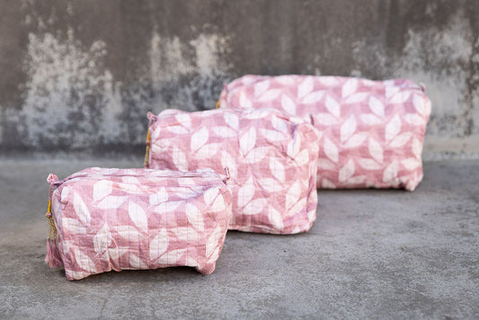 Set of three multi-colored patterned cotton cosmetic bags. Smaller bags fit into the largest for easy storage. Leaf pattern on pink.