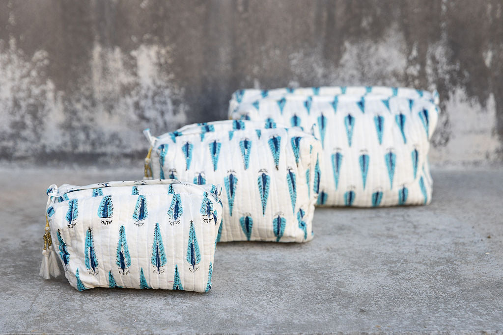 Set of three multi-colored patterned cotton cosmetic bags. Smaller bags fit into the largest for easy storage. Tree pattern on white.