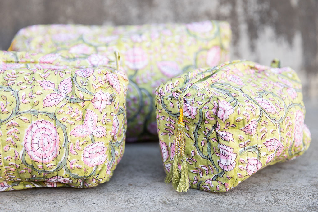 Set of three multi-colored patterned cotton cosmetic bags. Smaller bags fit into the largest for easy storage. Floral design on yellow. Detail