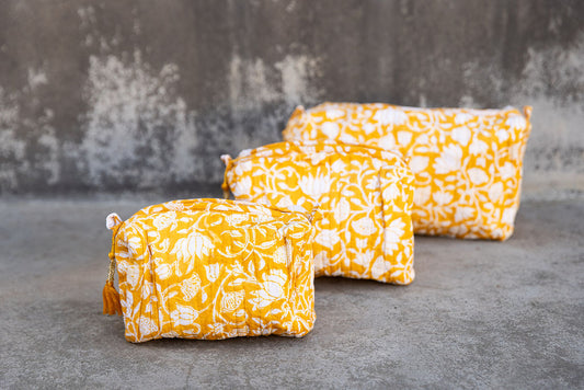 Set of three multi-colored patterned cotton cosmetic bags. Smaller bags fit into the largest for easy storage. White coral pattern on yellow.