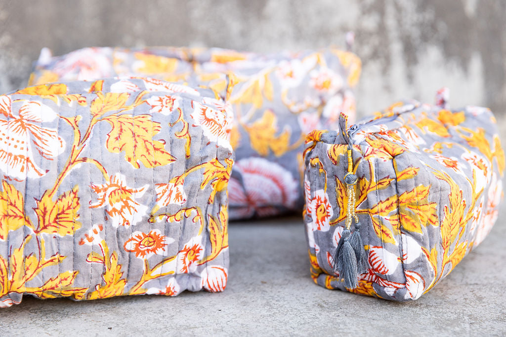 Detail of a set of three multi-colored patterned cotton cosmetic bags. Smaller bags fit into the largest for easy storage.