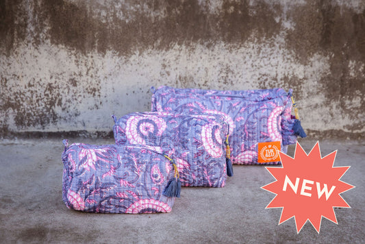 Set of three floral patterned cotton cosmetic bags. Smaller bags fit into the largest for easy storage. Purple and pink pattern.